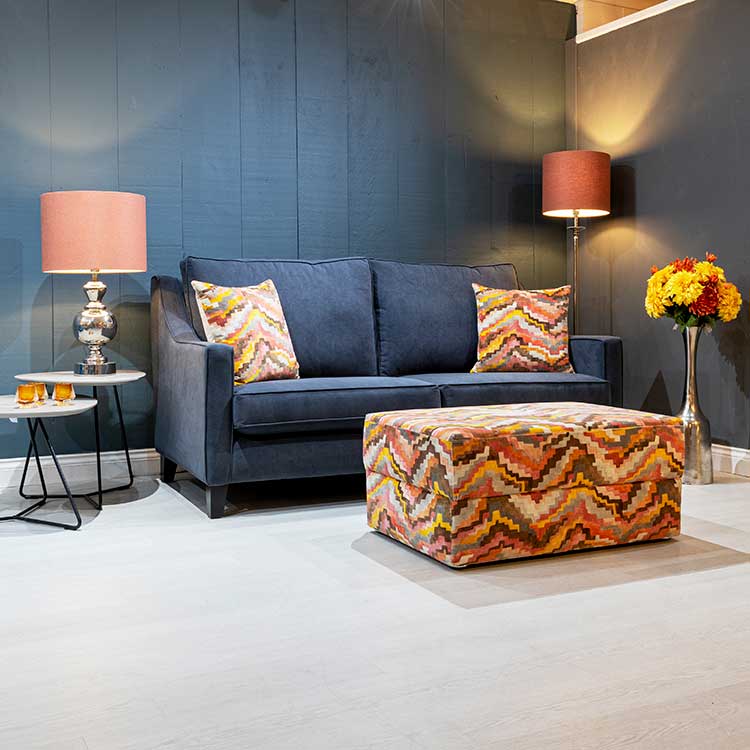 Blue bespoke sofa with contrasting orange custom made footstool and cushions