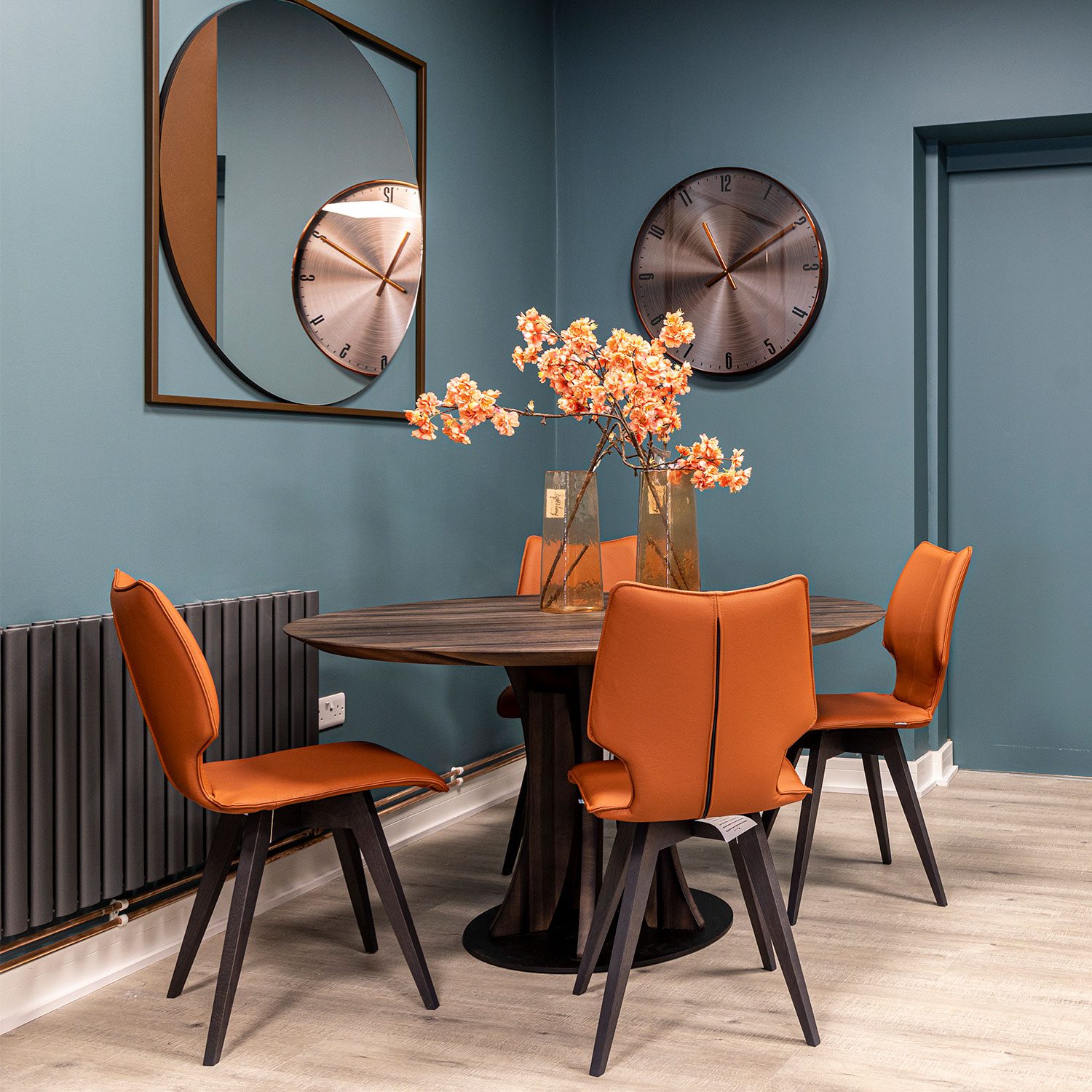 Round walnut dining table with orange leather dining chairs on display at the New England furniture showroom in Horsham