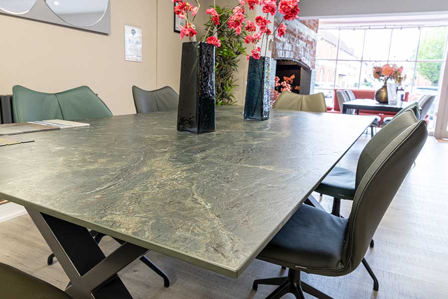 Large modern dining table mixes materials with a black metal frame and Neolith sintered stone top