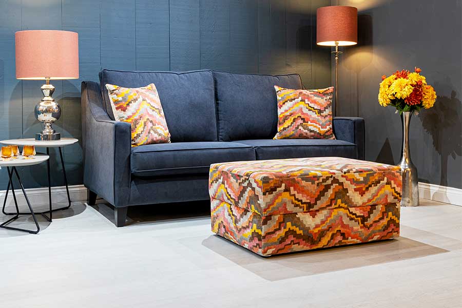 A bespoke ottoman footstool in upholstered in bright orange patterned fabric